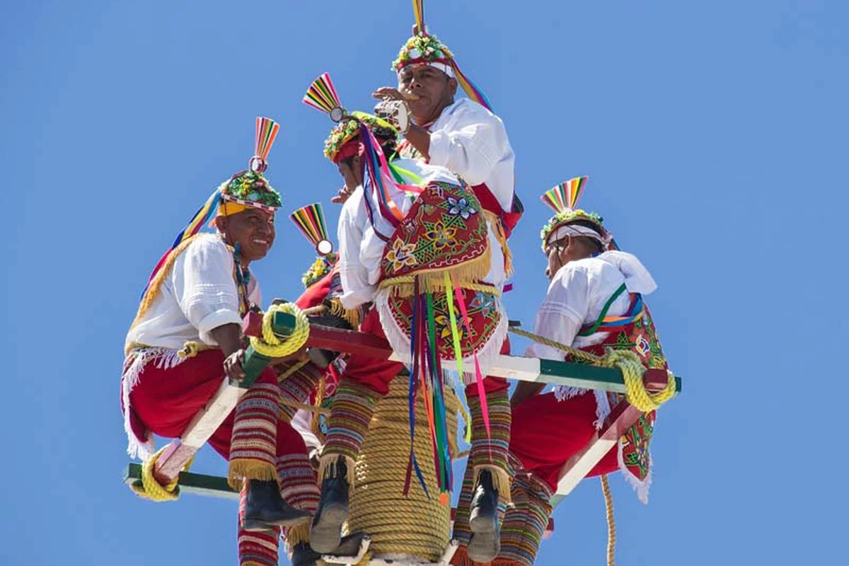 Voladores performers in traditional dress atop a ceremonial pole against a clear blue sky in Puerto Vallarta