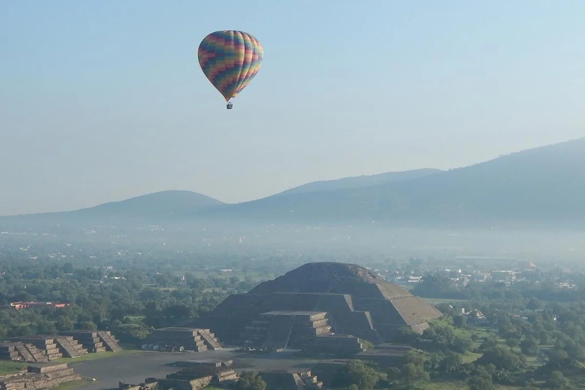 A colorful hot air balloon floating over the Pyramid of the Moon at the Teotihuacan archaeological site near Mexico City